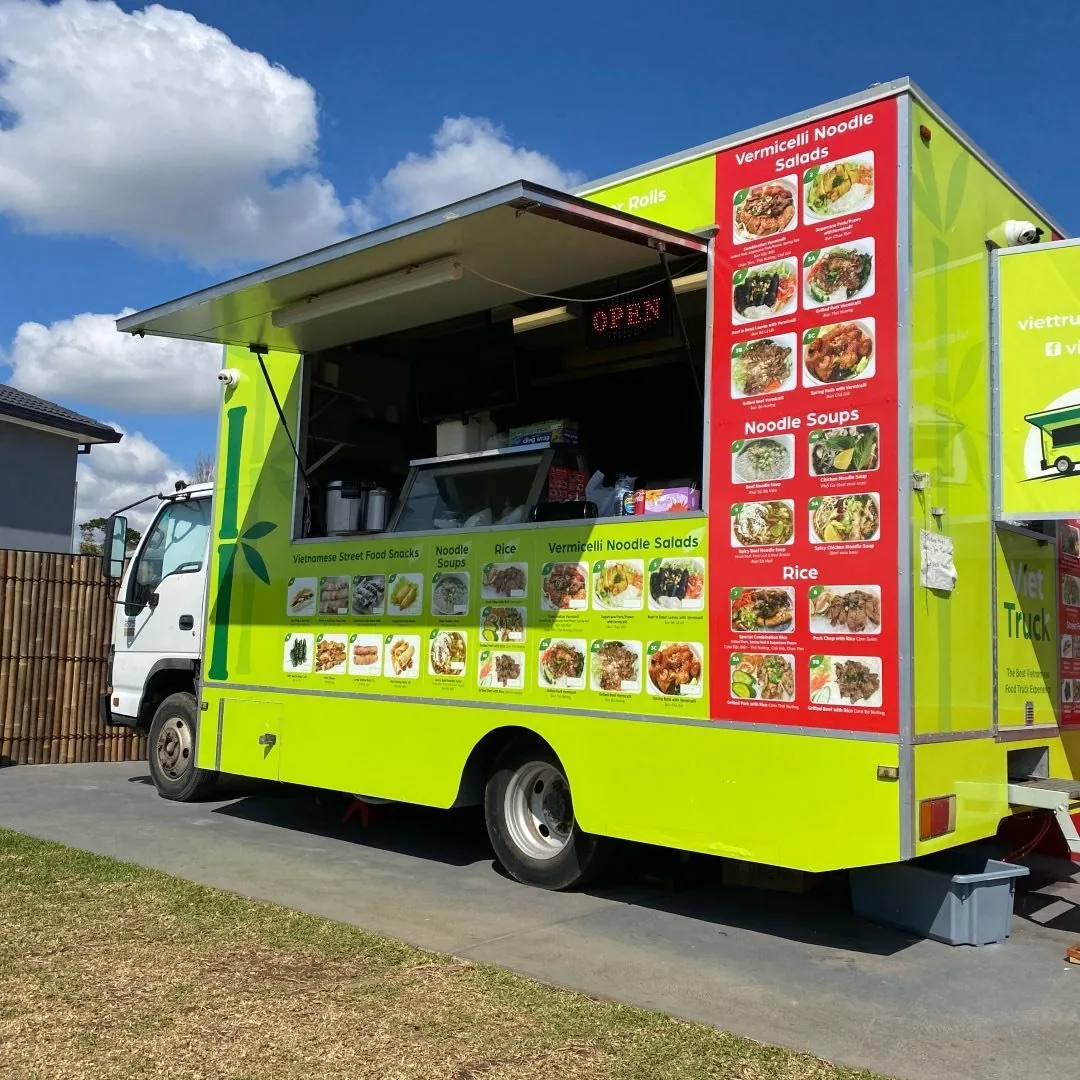 Our bright green VietTruck food truck parked on the grass, menu panels down the side and the serving window open